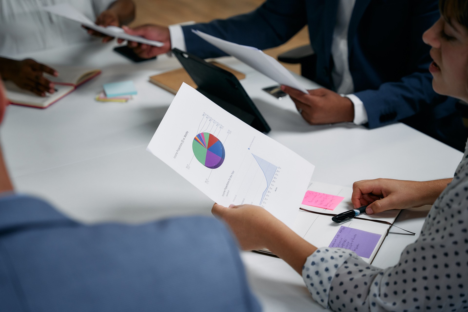 Four multiracial adults reviewing document with graph during business meeting in office